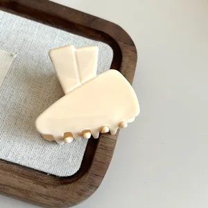 Close-up detail shot of the elegant beige acetate hair claw clip, featuring a unique design.