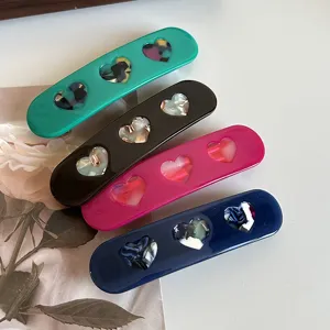 Detail view of sweet acetate hair clips with heart patterns in multi colors, perfect for styling.
