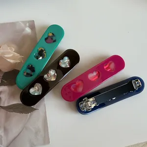 Detailed view of fashionable acetate hair spring clips featuring hollow heart designs.