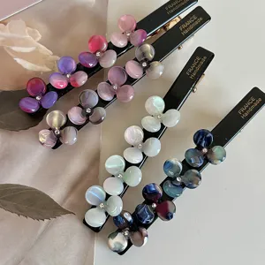 Close-up detail of colorful acetate flower duckbill hair clips with sparkling crystal rhinestones.
