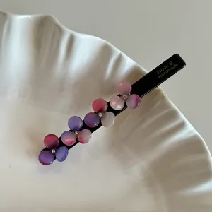 Detail view of black acetate hair clip with gradient pink resin flowers and sparkling crystals.