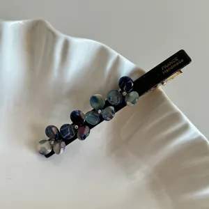 Detailed view of black acetate flower hair clip with colorful resin floral and rhinestone accent.