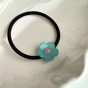 Détail de chouchou floral mignon, avec bande élastique noire et fleur vert menthe.