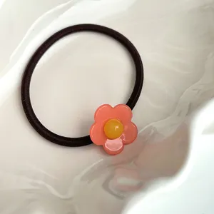 Vue détaillée d'un élastique à cheveux floral mignon avec une jolie breloque fleur rose.