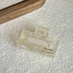 Detail view of a small acetate hair claw clip with pearlescent texture, perfect for holding bangs.
