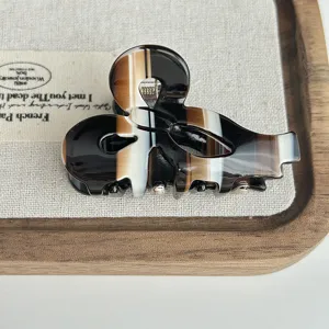 Detail view of a unique ampersand shaped acetate hair claw clip with chic marbled pattern.
