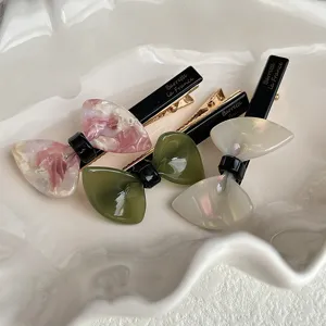 Detailed shot of Korean style resin bow hair clips in multiple colors placed on white dish.