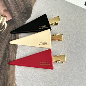Detail shot of elegant triangle hair clips in black, beige and red with gold clips.