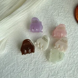 Detail shot of small acetate hair claws in various translucent colors, chic hair accessory.