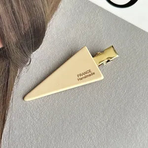 Close-up detail of the beige triangle hair clip featuring elegant handmade style and gold.