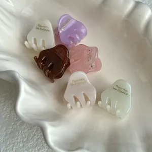 Detail shot of cute mini acetate hair claw clips in assorted pastel colors placed in shell dish.