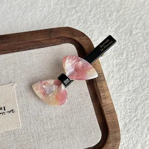 Korean style bow hair clip with pink marbled acrylic and black metal duckbill design.