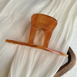 Detail view of retro amber acetate hair claw clip, elegant arch design for chic hairstyles.
