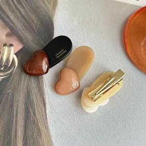 Close-up detail of stylish heart-shaped hair clips in charming brown and beige colors.