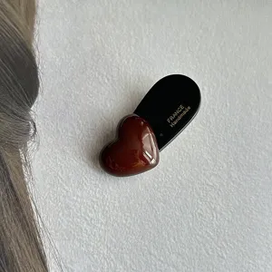 Close-up detail shot of a chic dark brown heart hair clip showcasing fine handmade texture.