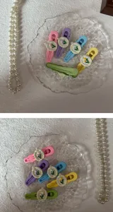 Close-up detail of cute pastel tulip hair clips set on a clear glass plate with pearls.
