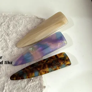 Close-up detail of stylish acetate hair clips in marbled beige, purple gradient, and tortoise.