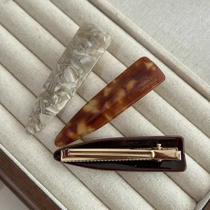Closeup detail of elegant acetate hair clips showcasing tortoiseshell and marble patterns.