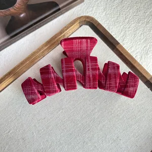 Close-up view of red plaid velvet hair claw clip detail, showing soft textured fabric and teeth.