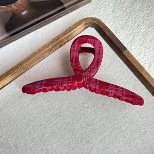 Detailed view of a red plaid velvet hair claw clip, showcasing soft fabric and strong spring.