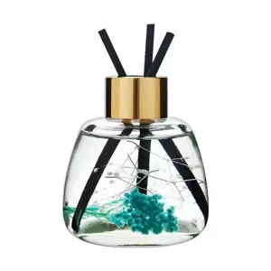 Glass reed diffuser bottle with dried flowers and black sticks for home fragrance decor.