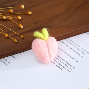 Close-up of handmade pink wool felt peach accessory for cute hat craft and DIY decor details.