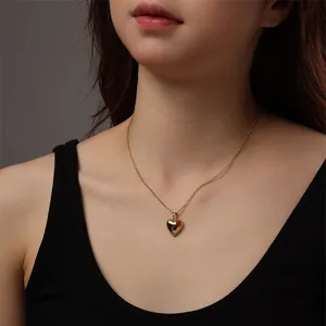 Primo piano di collana con ciondolo a cuore dorato sul collo, dettaglio di gioielli alla moda.