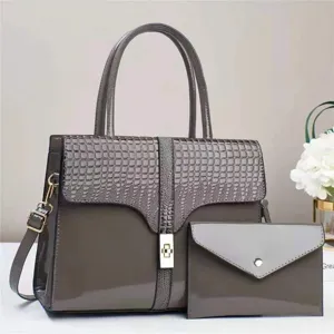 Detalle de bolso de charol gris con solapa efecto cocodrilo, cierre metálico.
