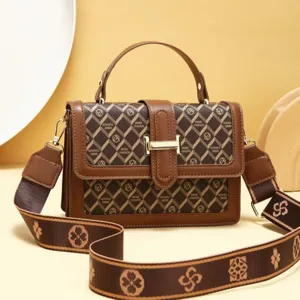 Élégant sac bandoulière marron pour femme avec poignée supérieure et large sangle imprimée.