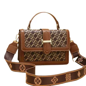Sac à main marron élégant style patchwork avec bandoulière large et imprimé géométrique.