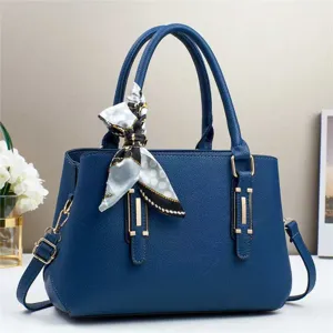 Primo piano dettagliato della borsa in pelle blu con dettagli dorati e un foulard.
