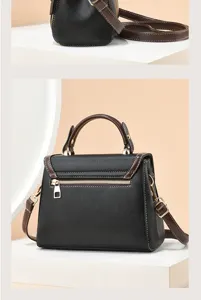 Gros plan détail du sac à bandoulière noir avec poignée marron et coutures contrastées.