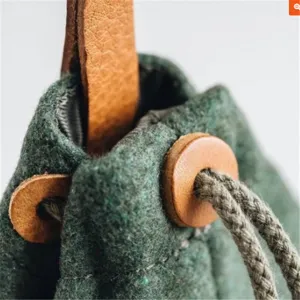 Detail van vilt honden snoepjes tas met duurzame groene stof en bruine lederen sluiting.