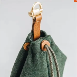 Detailopname van de groene vilt hondensnoepjes tas met bruine lederen riem en gouden haak.