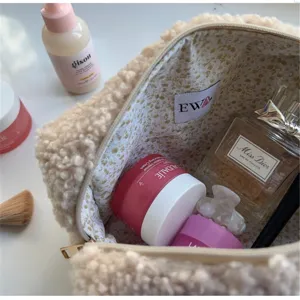 Detailed view of beige teddy fleece cosmetic bag interior filled with makeup items and floral lining.