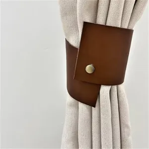 Close-up view of a Nordic style brown PU leather curtain tieback with a metal snap button detail.