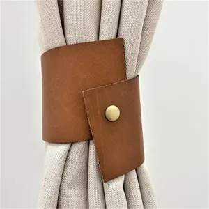 Close-up of brown PU leather curtain tieback showing fine texture and durable metal snap.