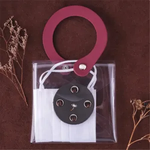 Detail shot of the transparent PVC face mask storage pouch with elegant maroon leather handle.