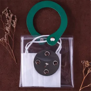 Detail view of clear PVC face mask storage pouch with green leather handle and button closure.