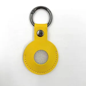 Yellow leather protective case and round keychain for smart tracker, stylish and durable accessory.