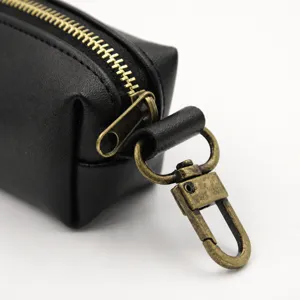Black leather dog waste bag holder with metal hook and zipper for pet walking outdoors.