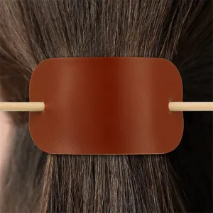 Detailaufnahme der braunen Leder Haarspange mit Holzstab, perfektes Design für Pferdeschwanz Frisur.