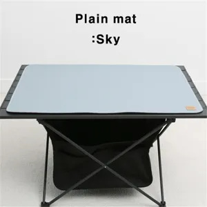 Detailed shot of sky blue leather camping mat laid on outdoor folding table surface.