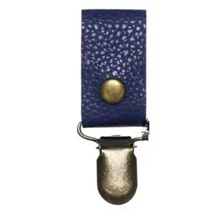 Primo piano dettagliato della clip per cappello in pelle blu con ferramenta in metallo bronzo.