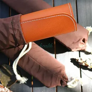Detailed closeup of rolled leather picnic mat in storage pouch on wooden table outdoors.