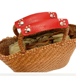 Close-up detail of woven basket bag with red leather paw print rivet handle cover accessory.