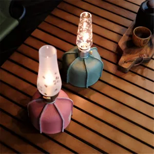 Outdoor camping gas tank leather cover and glass lamp shade detail in cozy wooden table view.