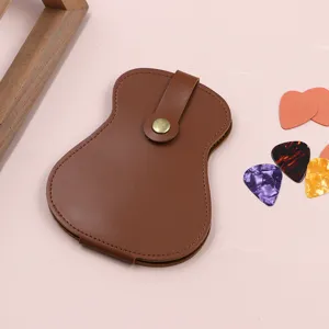 Brown leather guitar pick storage case with metal snap closure and colorful picks. Detail view.