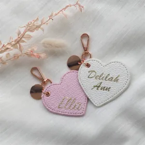 Primo piano di portachiavi in ecopelle a forma di cuore personalizzati con dettagli dorati.