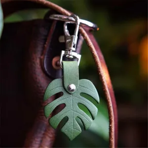 Πράσινο δερμάτινο μπρελόκ φύλλο monstera και κομψό κρεμαστό τσάντας με μέταλλο.